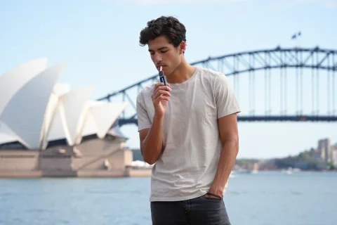 Person using disposable vapes Sydney with Sydney Opera House in background
